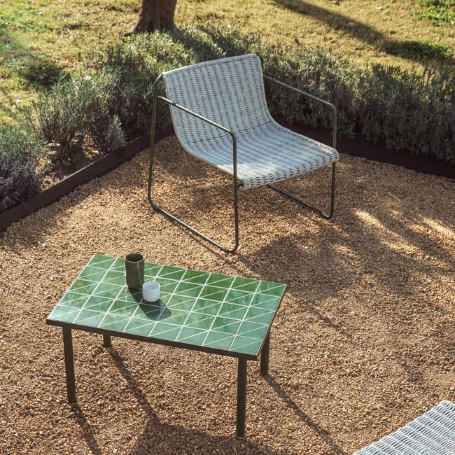 Groene MAURINA bijzettafel met tegels en metalen onderstel, inclusief rotan stoel op een grindterras.