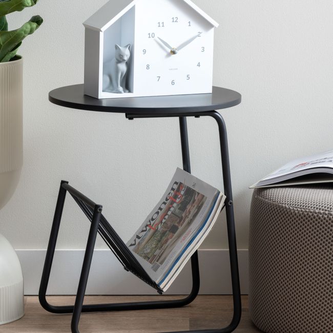 Zwarte metalen bijzettafel met rond blad en een tijdschriftenrek aan de zijkant.
