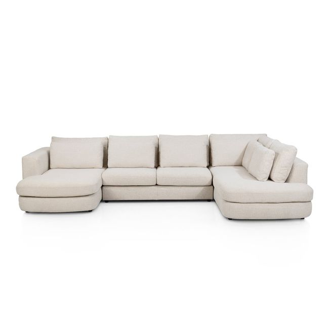 Crèmekleurige stoffen hoekzetel met chaise longue en losse kussens.