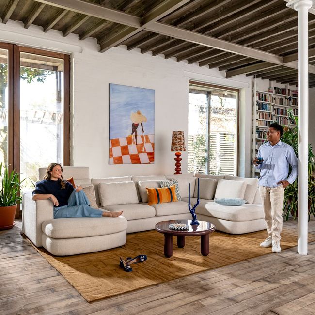 Crèmekleurige fluwelen hoekbank ADINO met twee personen in een woonkamer.