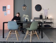 Zwart metalen eetkamertafel STORM, met houten onderstel en twee gekleurde kunststof stoelen.