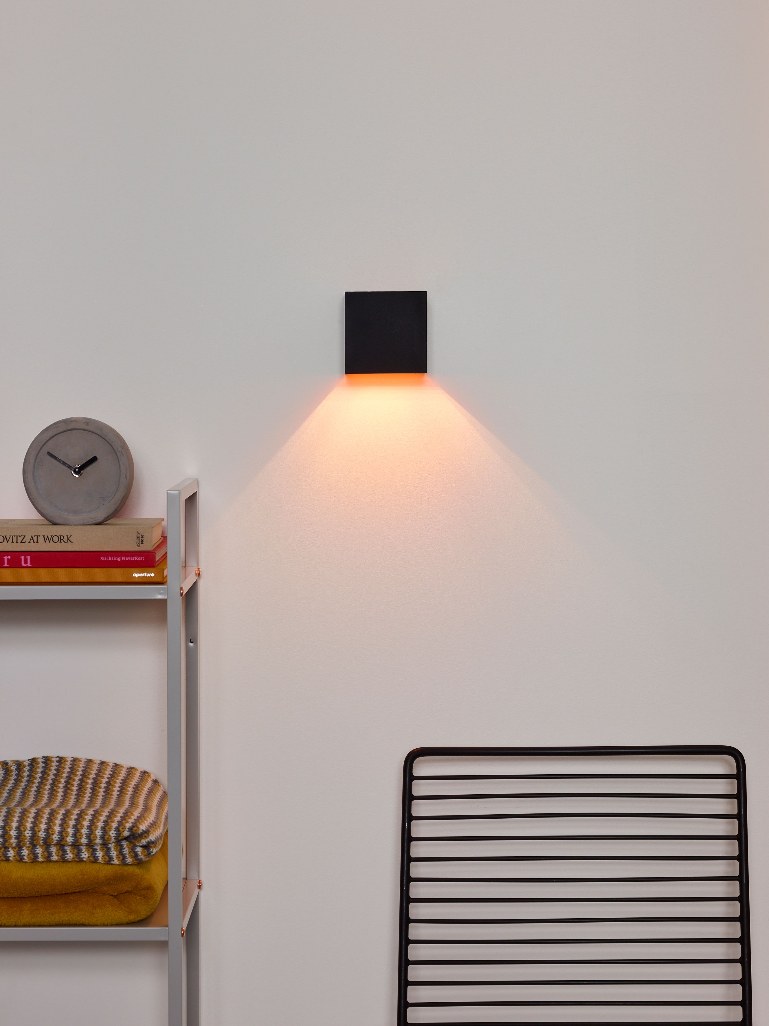 Wandlamp XIO van aluminium, grijs, met warm licht naar beneden schijnend.