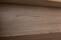 Detail van een eikenhouten plank in een boekenkast met nerven en lichte kleurschakeringen.