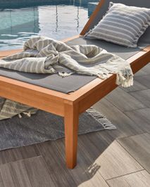 CATERIN ligstoel van eucalyptus met grijs kussen en plaid bij zwembad.