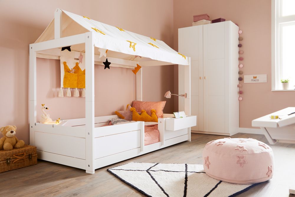 Roze knijplamp met zilverkleurige accenten aan het hoofdeinde van een kinderbed.