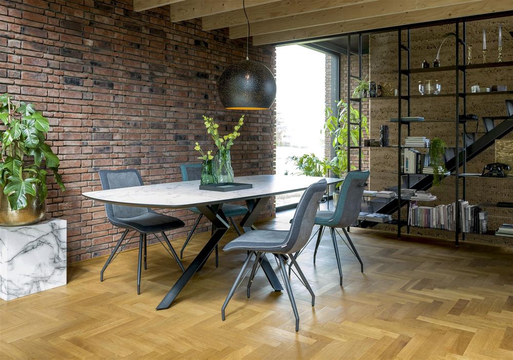 Eetkamertafel met wit marmerlook blad en zwart stalen onderstel met vier donkergrijze stoelen.