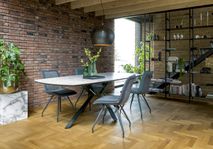 Eetkamertafel met wit marmerlook blad en zwart stalen onderstel met vier donkergrijze stoelen.