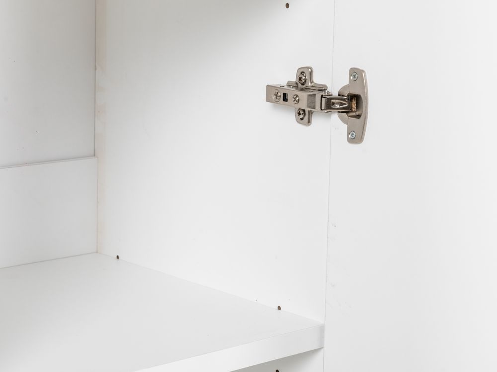 Detail van een zilverkleurig meubelscharnier op een wit melamine boekenplank.