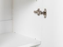 Detail van een zilverkleurig meubelscharnier op een wit melamine boekenplank.