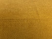 Detail van de hoekzetel ADA, geel gekleurd met een grove textuur stof en een naad.