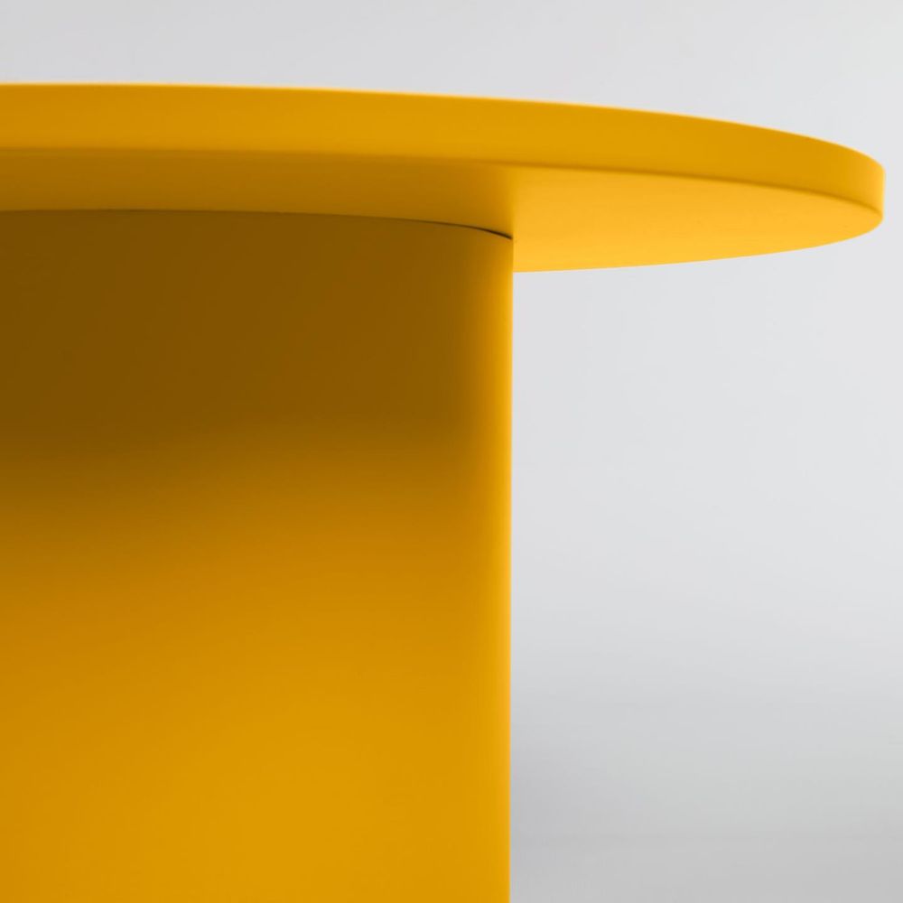 Ronde mosterdgele metalen salontafel, close-up van blad en poot.