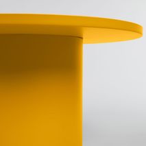 Ronde mosterdgele metalen salontafel, close-up van blad en poot.