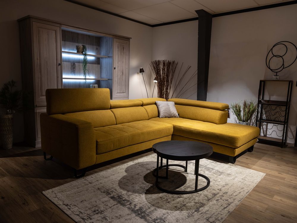 Ada hoekzetel van gele stof in een woonkamer met salontafel, vloerkleed en kast.