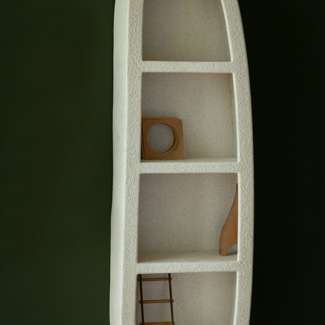 Beige wandkast VEDA van houtfineer met vier schappen, staand tegen een donkergroene achtergrond.