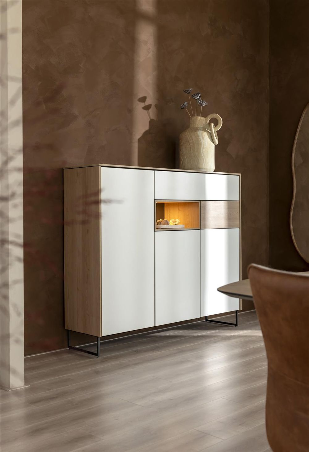 Wandkast van wit hout en eikenlook met verlicht open vak en metalen poten.