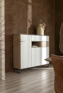 Wandkast LINDENFIELD van hout in wit en eikenlook met metalen onderstel en een vaas met bloemen.