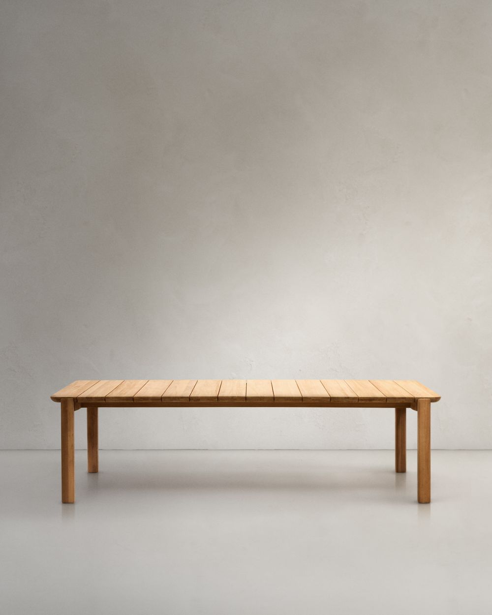 Massieve, naturel teakhouten tuintafel met een blad van latten en vier robuuste poten.