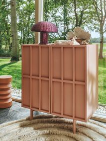 Roze houten wandkast 'Blush' met twee deuren en een gevlochten tafellamp erop.