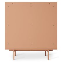 Roze metalen wandkast 'BLUSH' met slanke pootjes, achterzijde zichtbaar.