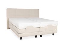 Elektrische beige stoffen boxspring met gestoffeerd hoofdbord en twee aparte matrassen.