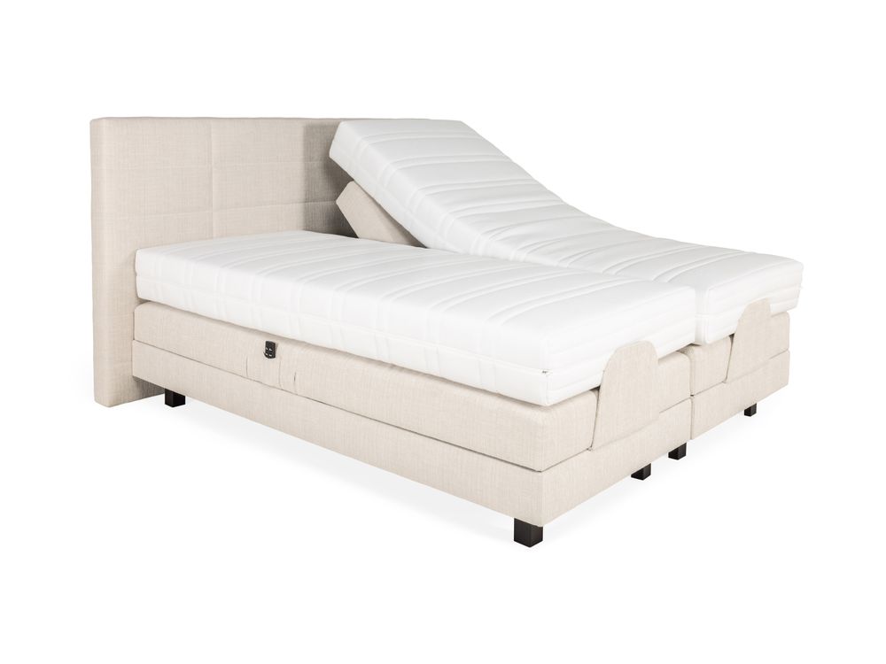Elektrische boxspring firm met beige textiel bekleding, één matras is versteld.