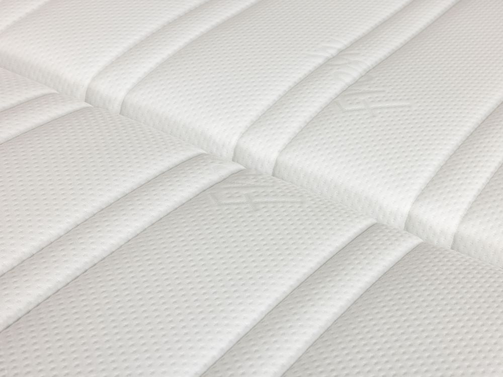 Detail van een wit gestoffeerd matras met stiknaden.
