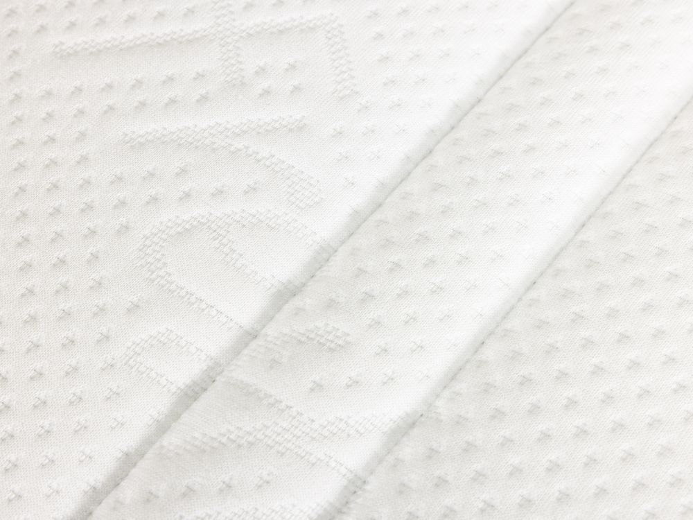Detail van structuur van de witte matrashoes met ingeweven patroon.
