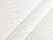 Detail van structuur van de witte matrashoes met ingeweven patroon.