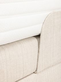 Onderkant van de matras en de geplooide stoffen hoes van de elektrische beige boxspring.