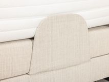 Beige elektrische boxspring met geweven stoffen bekleding en wit matras.