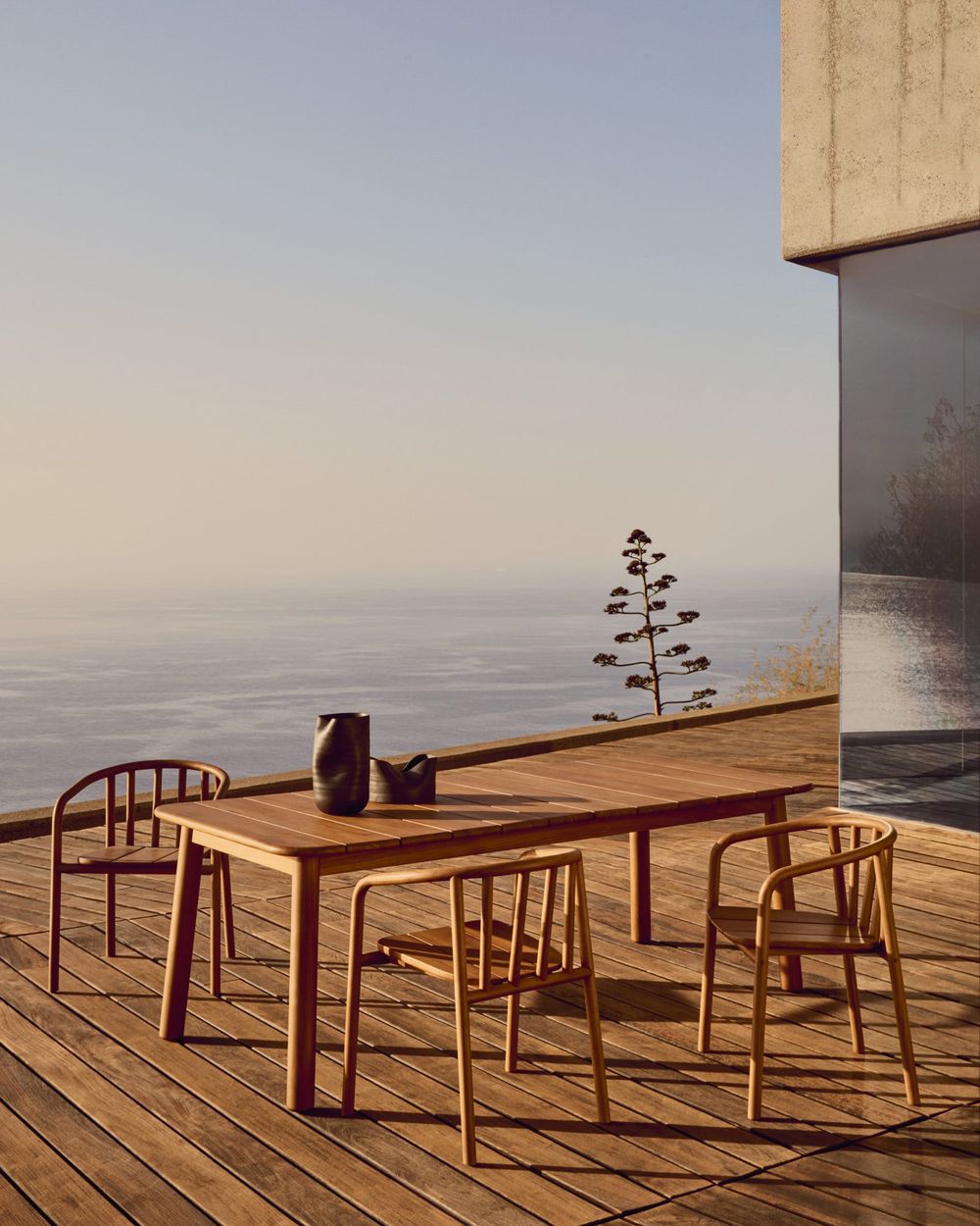 Houten tuintafel met vier bijpassende teakhouten tuinstoelen op een terras aan zee.