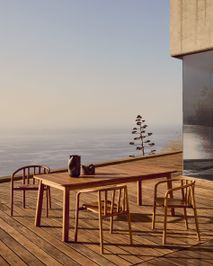 Houten tuintafel met vier bijpassende teakhouten tuinstoelen op een terras aan zee.