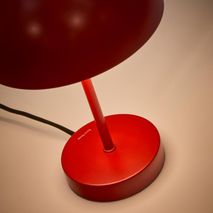 Rode metalen tafellamp met ronde voet en halfronde kap.