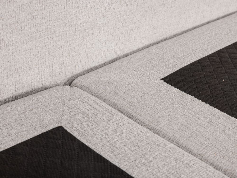Boxspring ASPEN met beige stoffen bekleding en zwarte, gewatteerde stof details.