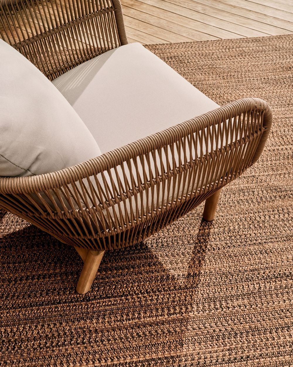 Loungefauteuil CATALINA in beige/acaciahout op een donkerbruin vloerkleed.